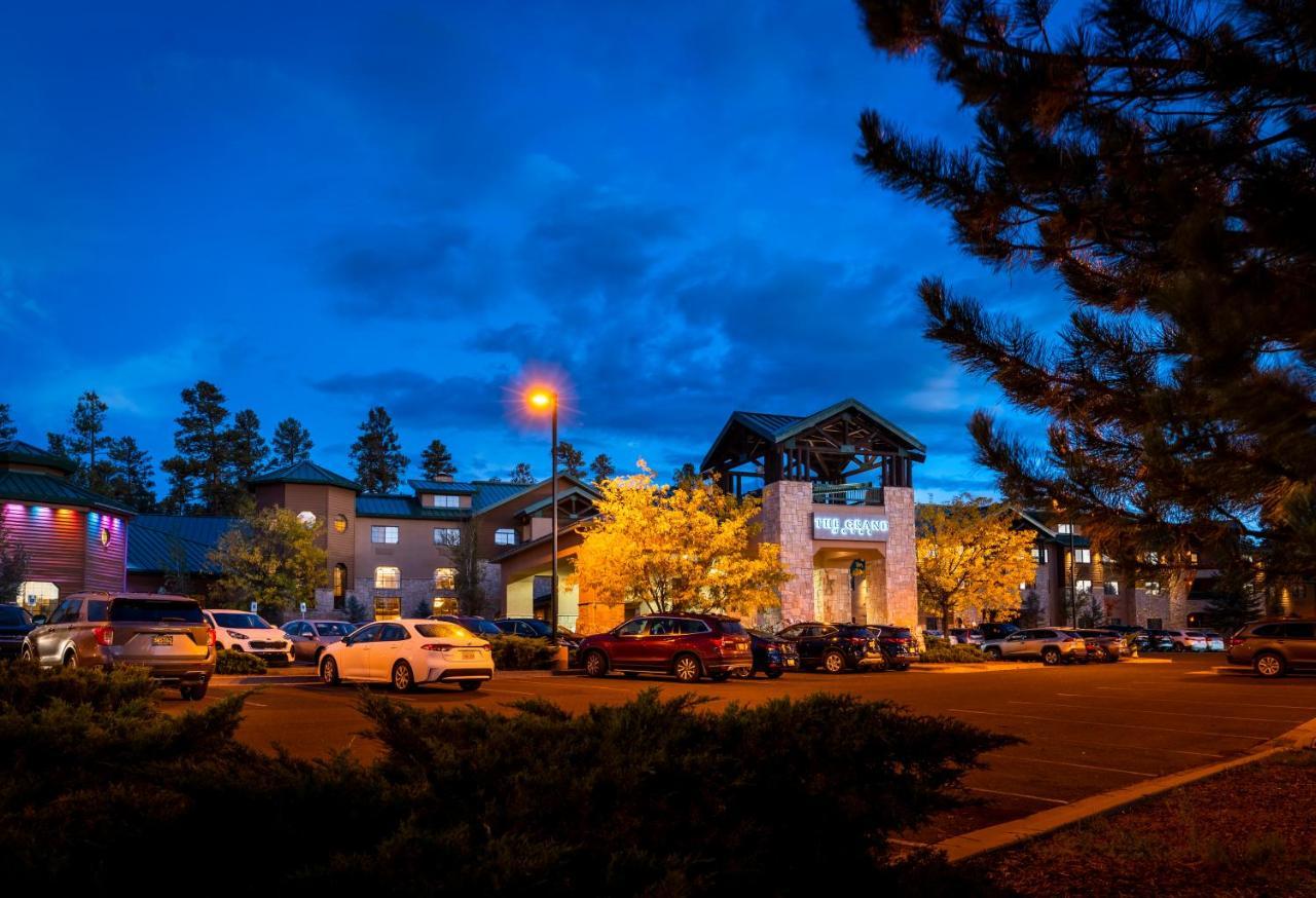 The Grand Hotel At The Grand Canyon Tusayan Dış mekan fotoğraf The photo shows a hotel or lodge building during twilight, with a blue sky and clouds. There are several cars parked in front, and some illuminated trees add warmth to the scene. The architecture features a combination of stone and wood elements, and